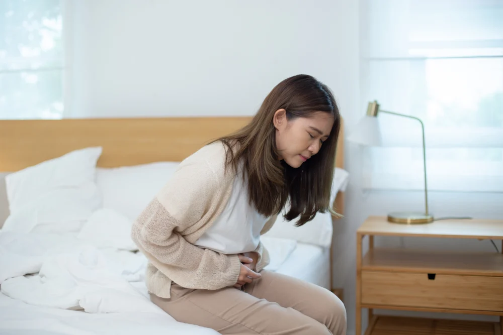 Woman holding her lower abdomen while experiencing persistent abdominal pain.