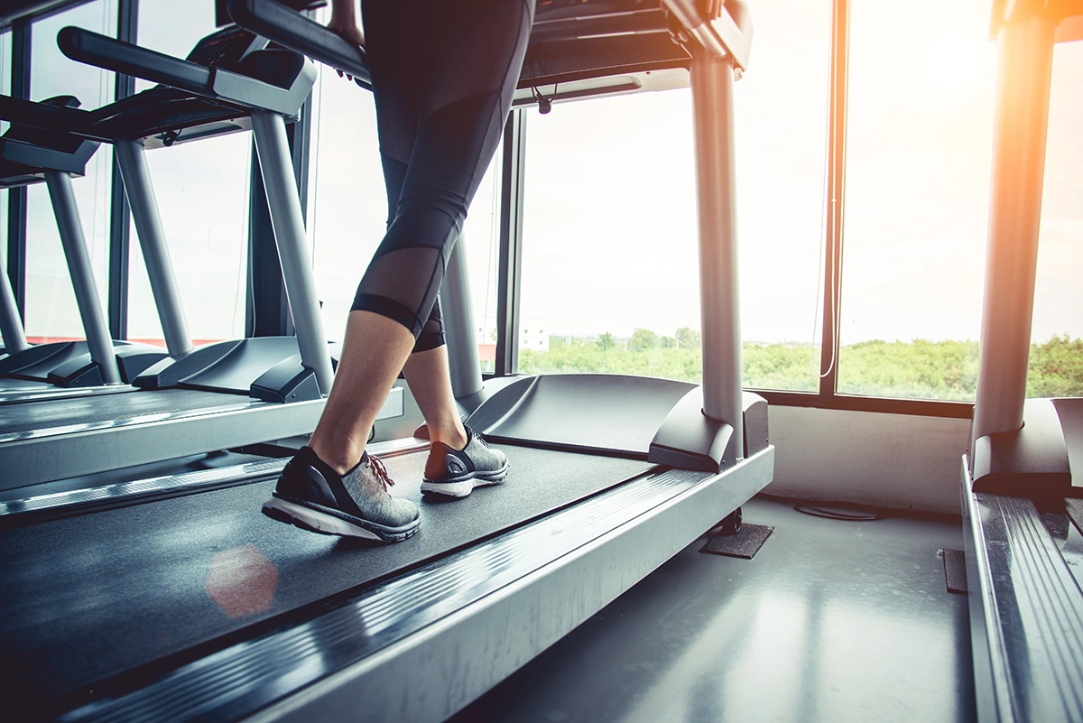 Close-up of a person’s feet running on a treadmill, illustrating indoor fitness and cardio exercise.