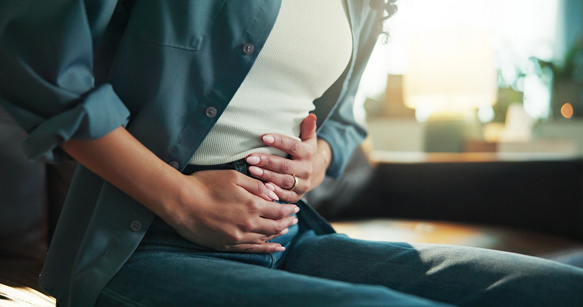 Woman holding her abdomen in pain, illustrating symptoms of abdominal cramps or irritable bowel syndrome.
