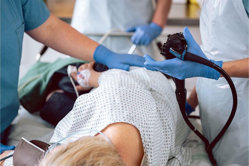 Patient lying on a hospital bed during a colonoscopy while a doctor performs the procedure.